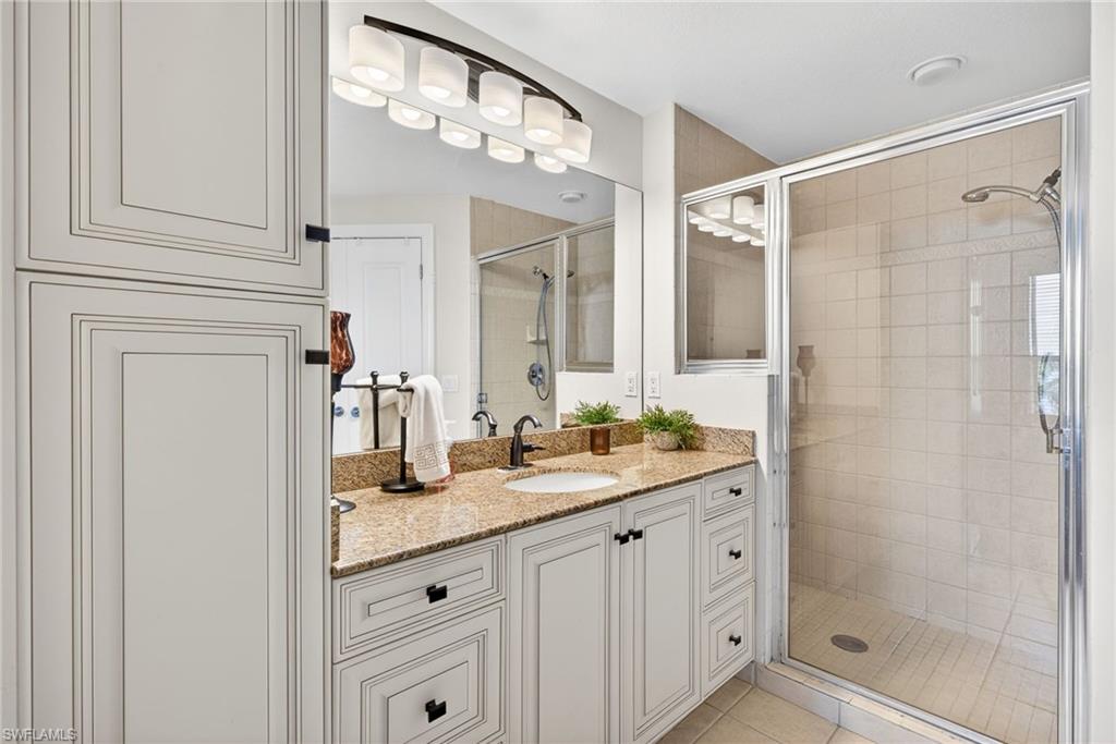 Full bath featuring vanity, a stall shower, and light tile patterned flooring