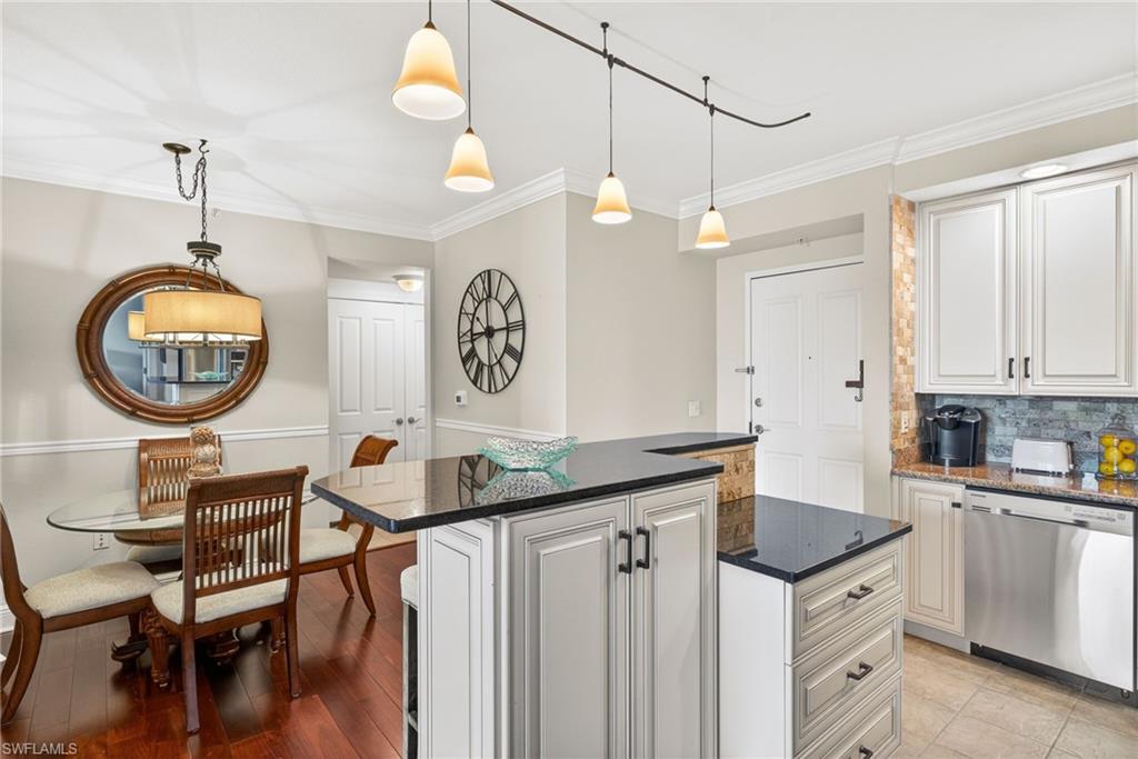 Kitchen featuring stainless steel dishwasher, a center island, backsplash, crown molding, and white cabinetry