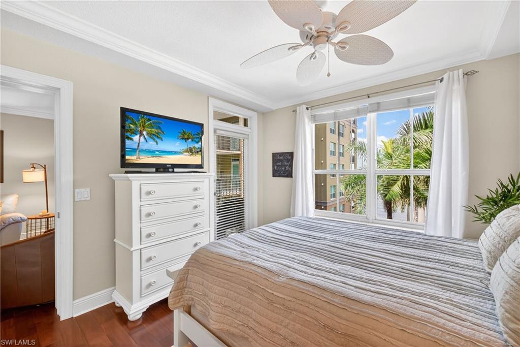 Bedroom featuring dark wood-style floors, ornamental molding, a ceiling fan, and multiple windows
