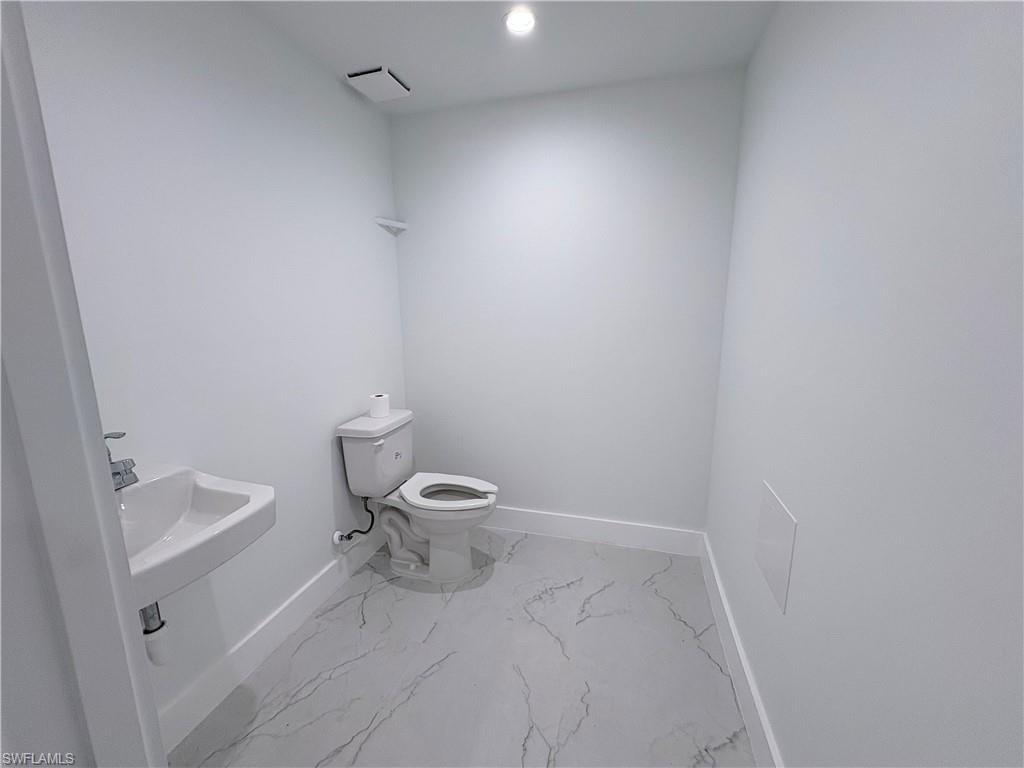 Half bathroom with recessed lighting and marble finish flooring