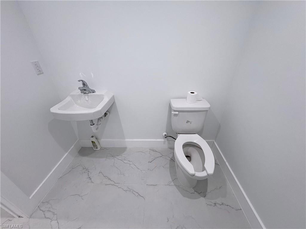 Bathroom featuring toilet and light marble finish floors