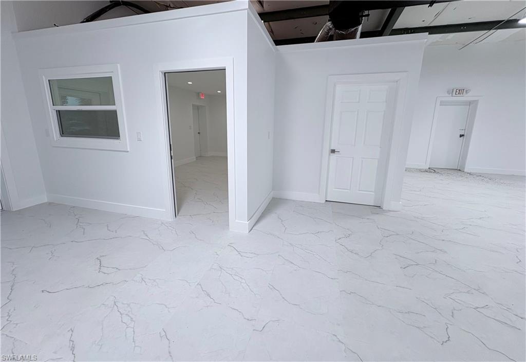 Spare room featuring baseboards and light marble finish flooring