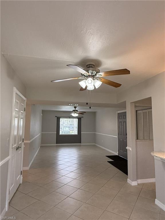 Empty room featuring light tile patterned floors and ceiling fan
