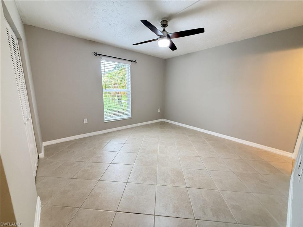 Unfurnished bedroom with a ceiling fan, light tile patterned floors, and a textured ceiling