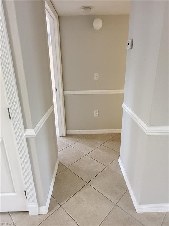 Hall featuring light tile patterned floors and baseboards.  Hall leads to 2 bedrooms and common bathroom