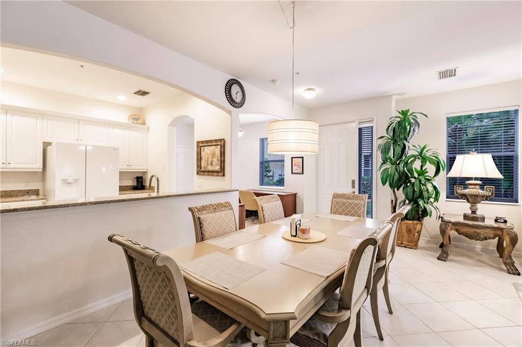 Dining space featuring light tile patterned floors and arched walkways