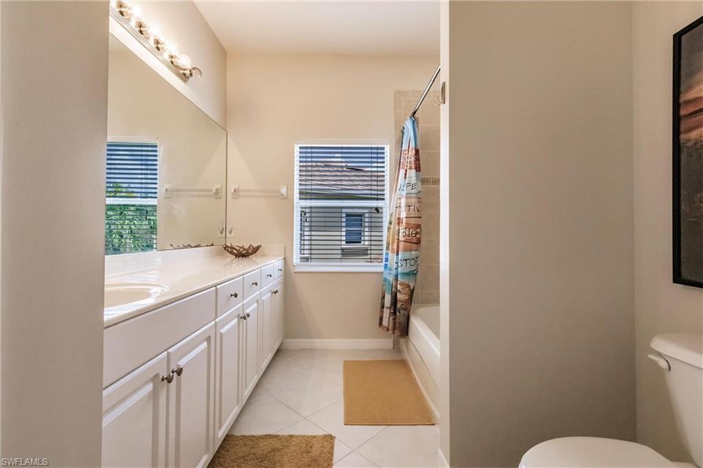 Bathroom with vanity, shower / tub combo with curtain, and light tile patterned floors