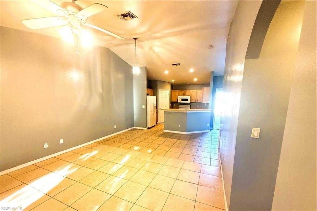 Unfurnished living room featuring vaulted ceiling, light tile patterned flooring, ceiling fan, recessed lighting, and arched walkways