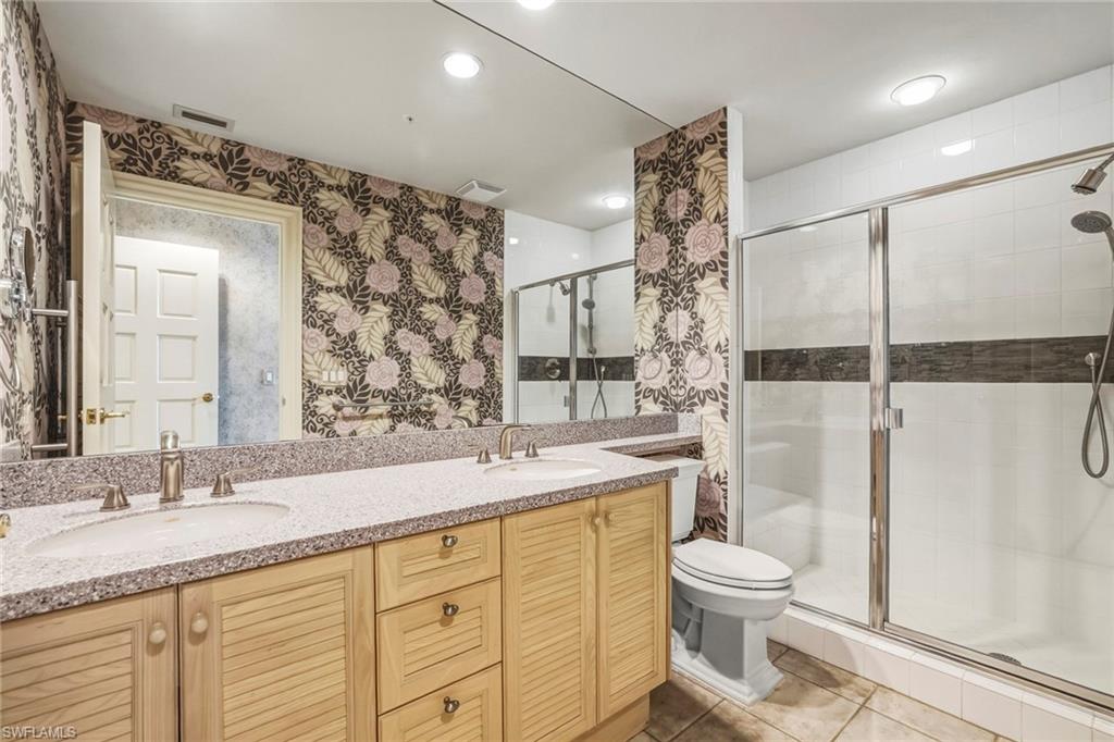 Bathroom with double vanity, a shower stall, recessed lighting, light tile patterned flooring, and wallpapered walls