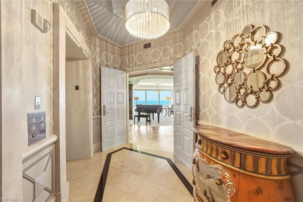 Entrance foyer featuring hanging lights, inlaid floor details, and wallpapered walls