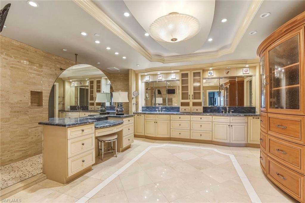 Full bathroom with inlaid floor details, double vanity, recessed lighting, a walk in shower, and a raised ceiling