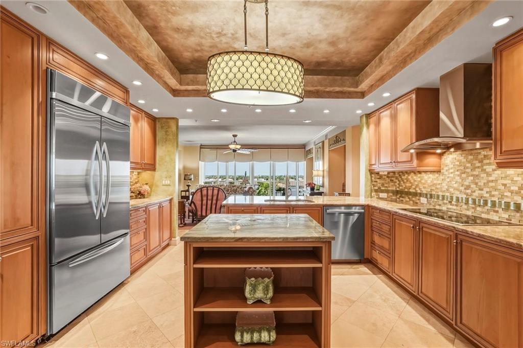 Kitchen featuring open shelves, stainless steel appliances, a kitchen island, light stone countertops, and a raised ceiling
