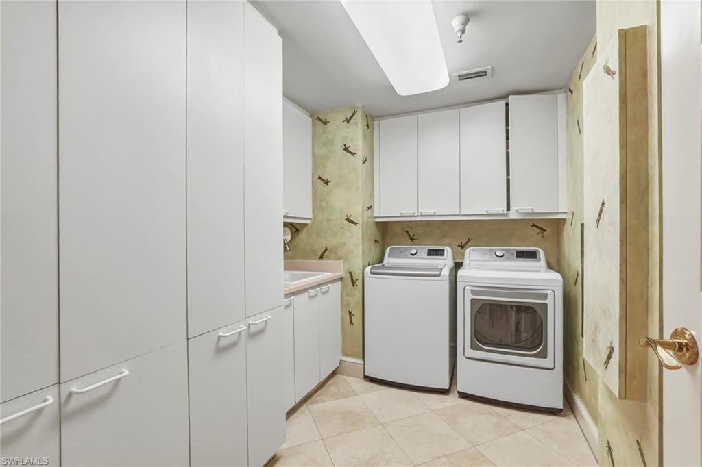 Laundry room with cabinet space, washer and clothes dryer, and light tile patterned floors