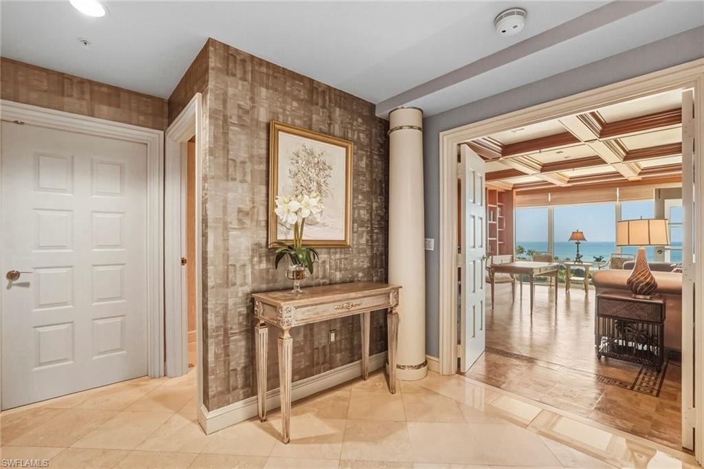 Hall featuring coffered ceiling, a water view, light tile patterned floors, and wallpapered walls