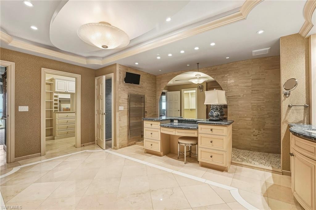 Full bathroom with vanity, recessed lighting, a walk in shower, a walk in closet, and a tray ceiling
