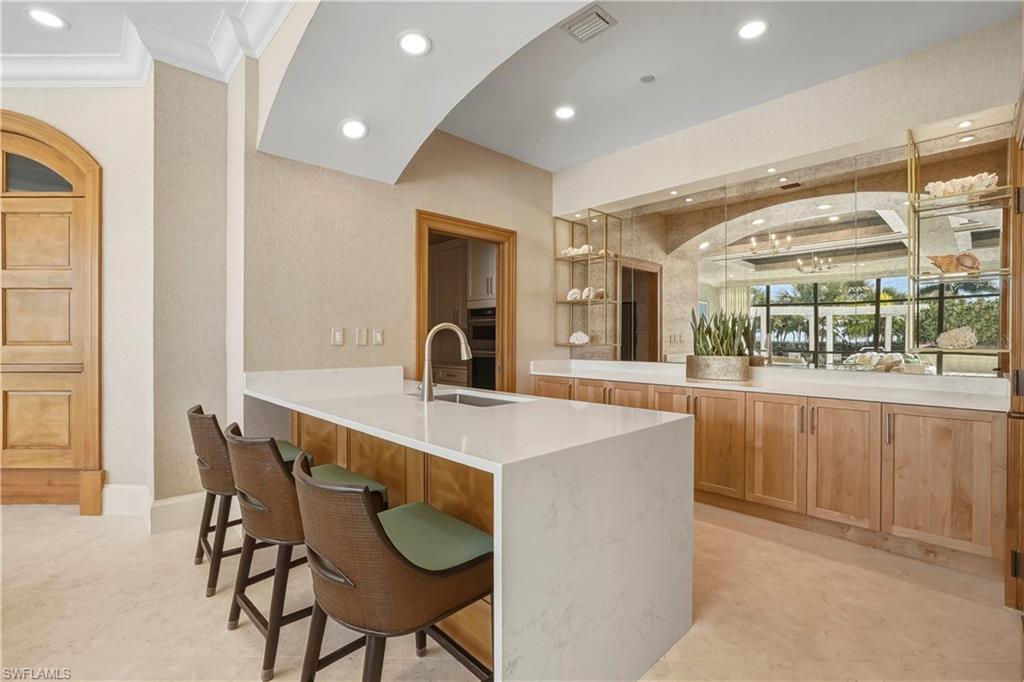 Kitchen featuring a peninsula, recessed lighting, a kitchen bar, light stone counters, and double oven