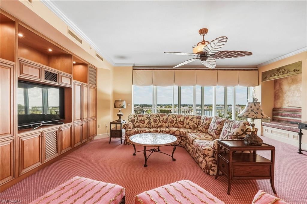 Living area with ornamental molding, light colored carpet, ceiling fan, and plenty of natural light