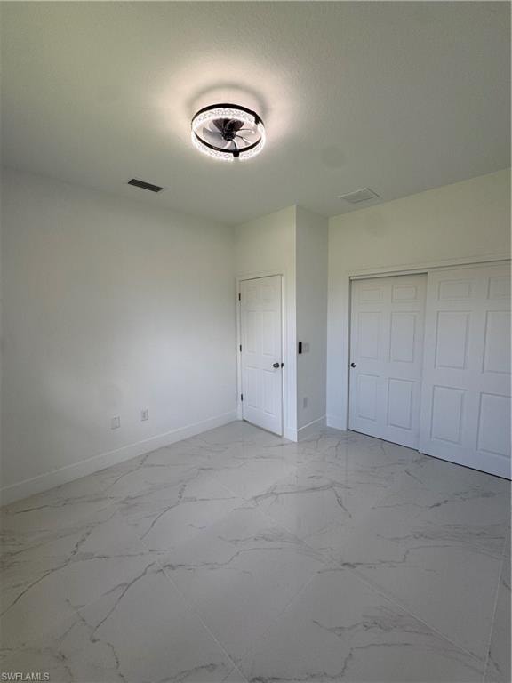 Unfurnished bedroom featuring light marble finish flooring and a closet