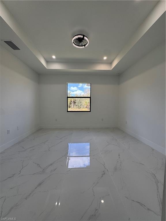 Spare room with light marble finish floors, a raised ceiling, and recessed lighting