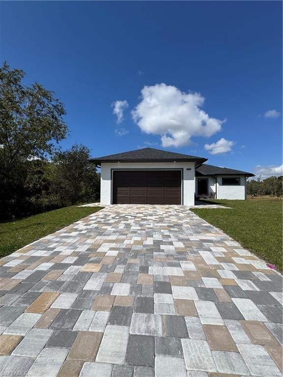 View of front of house featuring a front yard, decorative driveway, a garage, and stucco siding