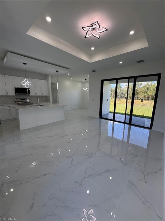 Unfurnished living room featuring recessed lighting and a raised ceiling