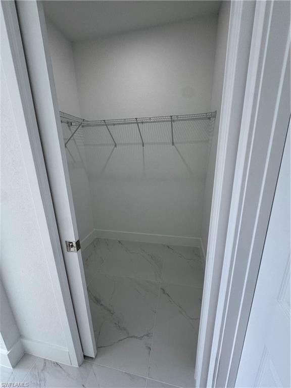 Walk in closet featuring light marble finish flooring