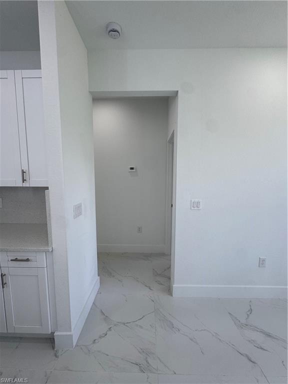 Hallway featuring light marble finish floors