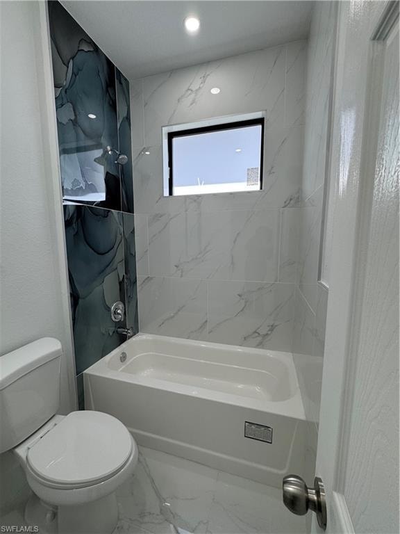 Full bath featuring marble look tiles and  shower combination