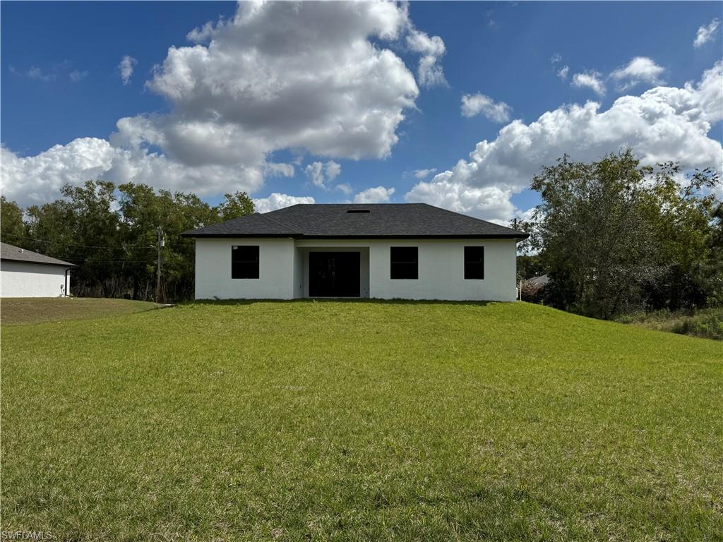 Back of property featuring a lawn and stucco siding