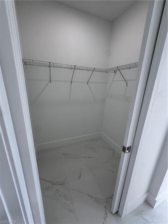 Walk in closet with light marble finish floors