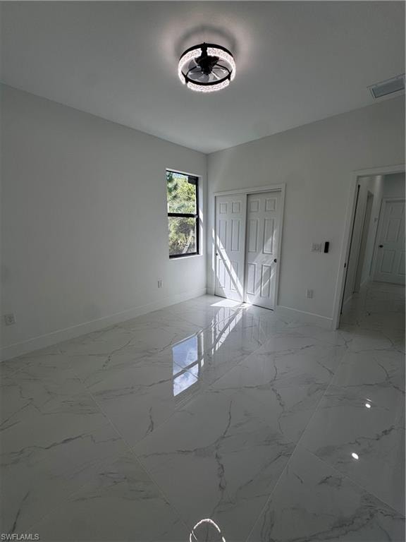 Unfurnished bedroom featuring a closet and light marble finish floors