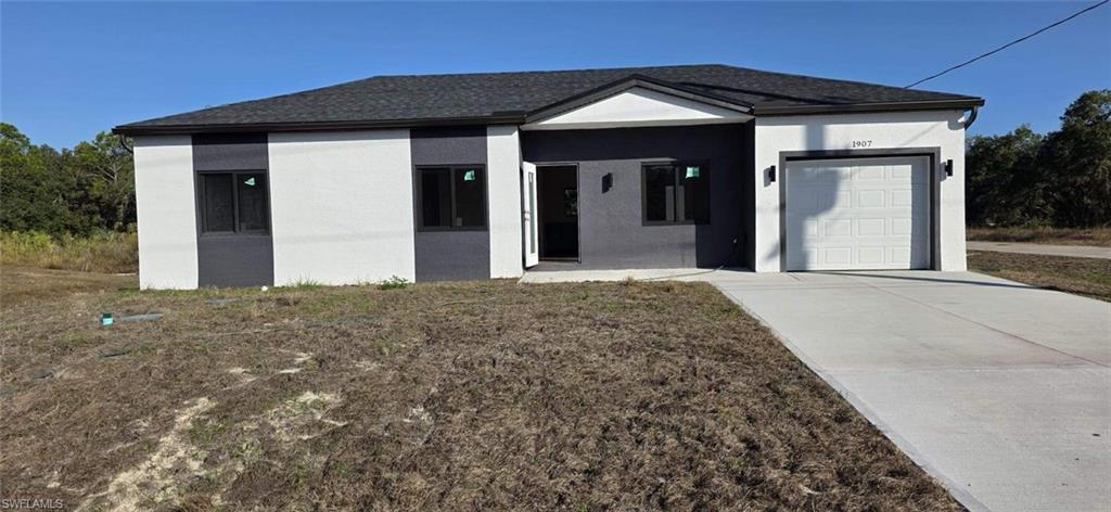 Ranch-style home featuring an attached garage, stucco siding, and driveway
