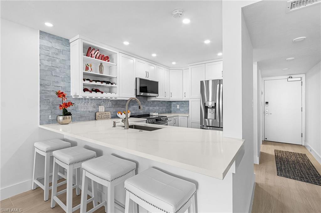 Bright white well lit kitchen with so much storage and space for 4 barstools in addition to dining area.