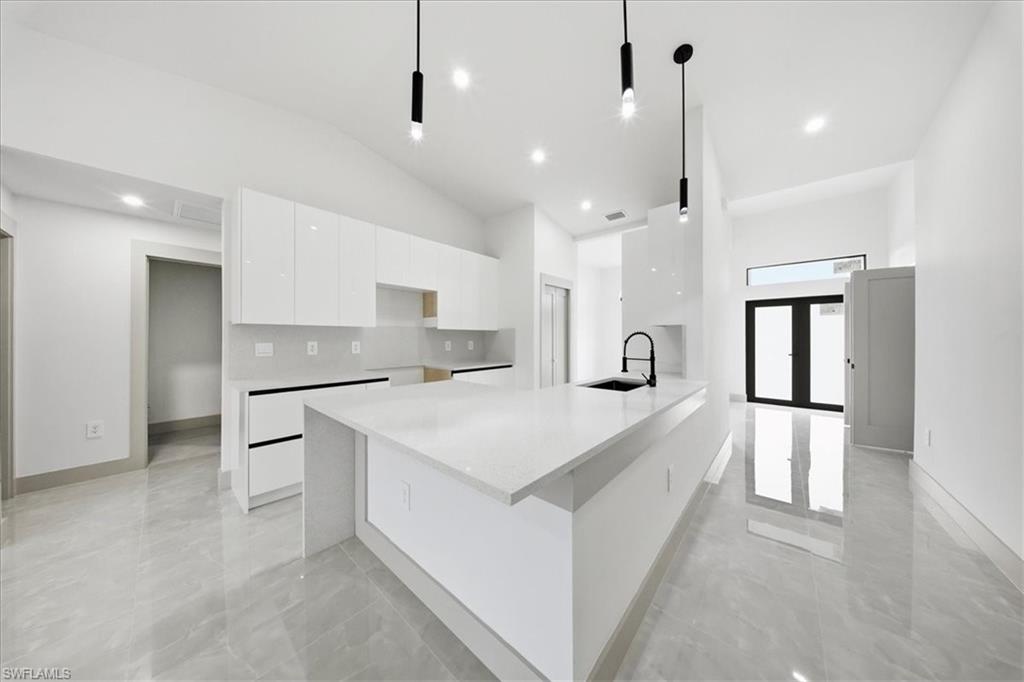Kitchen with light stone counters, white cabinets, modern cabinets, lofted ceiling, and a breakfast bar area