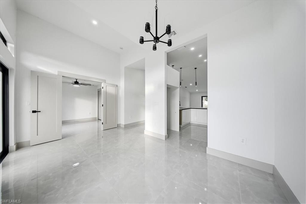 Unfurnished living room with a high ceiling, a chandelier, and a ceiling fan