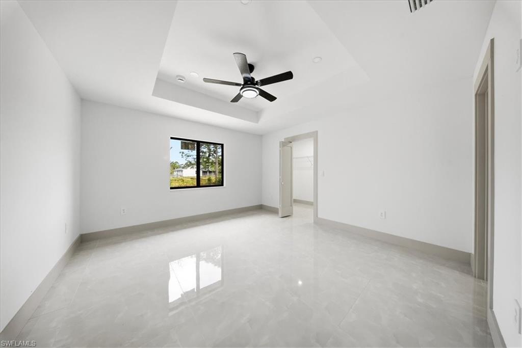 Empty room featuring a tray ceiling and ceiling fan