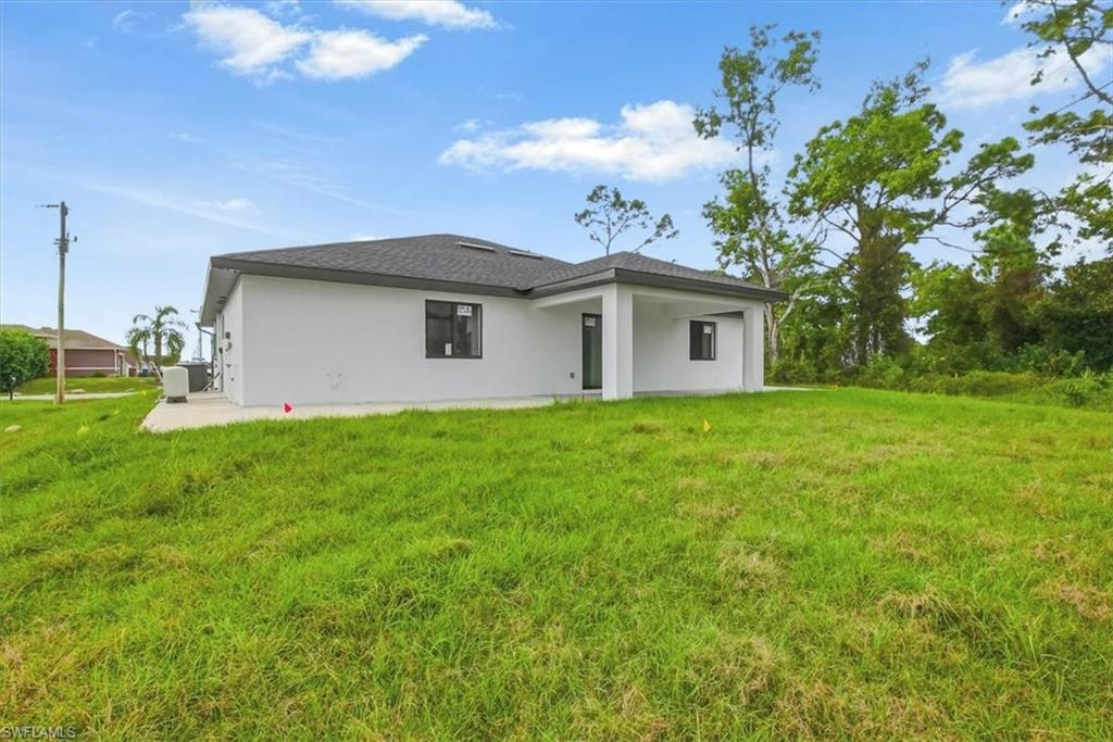 Back of house featuring a patio, a lawn, stucco siding, and a shingled roof