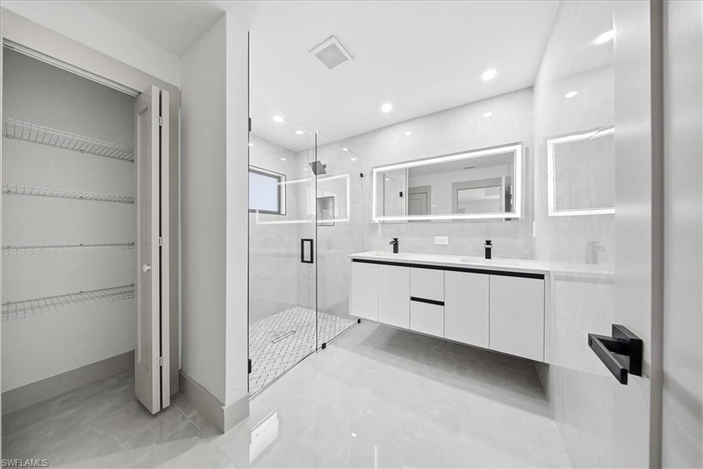 Full bathroom featuring a marble finish shower, double vanity, a spacious closet, and recessed lighting