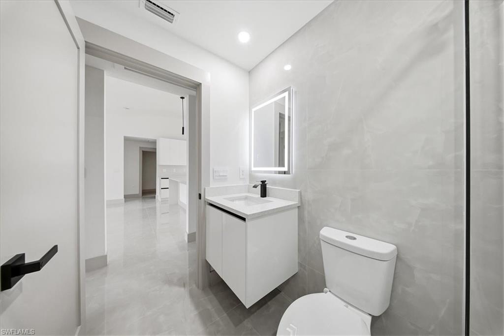 Half bathroom with vanity, tile walls, and recessed lighting