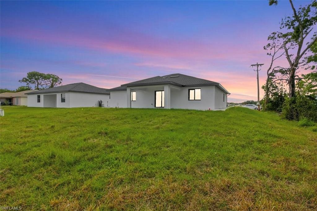 Rear view of house featuring a yard, a patio area, and stucco siding