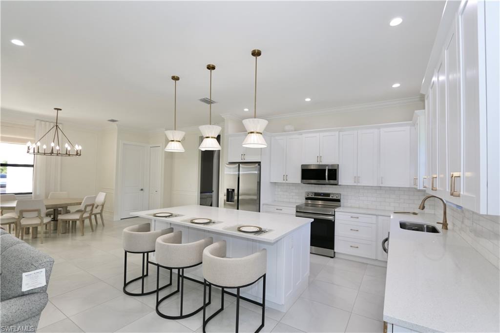 Kitchen featuring stainless steel appliances, white cabinets, a breakfast bar, a center island, and crown molding
