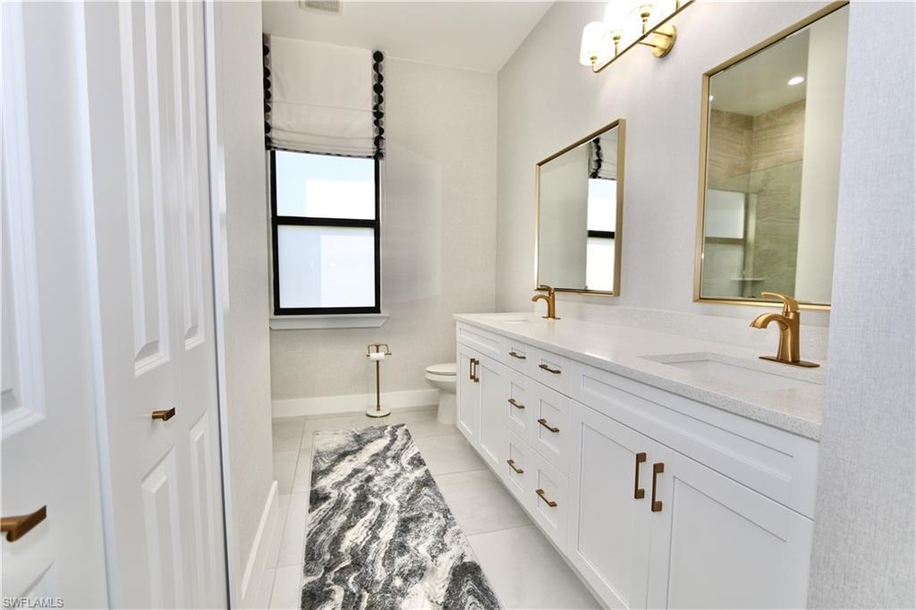 Full bathroom with double vanity and light tile patterned floors