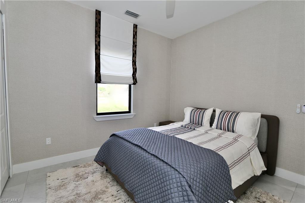 Bedroom with ceiling fan and wallpapered walls
