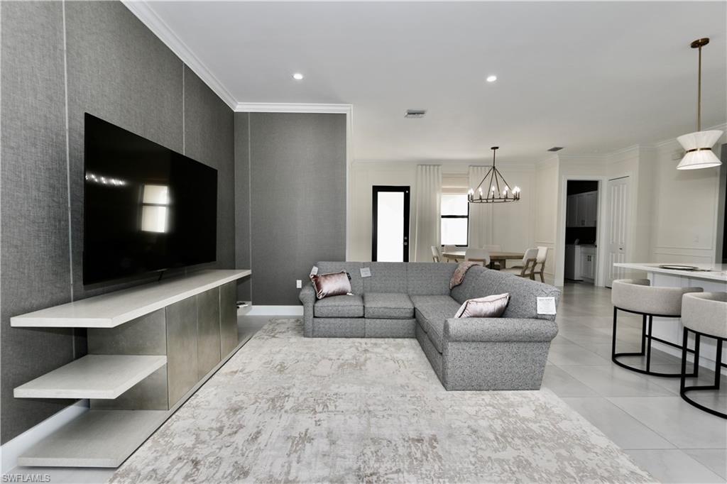 Living area with crown molding and suspended lighting