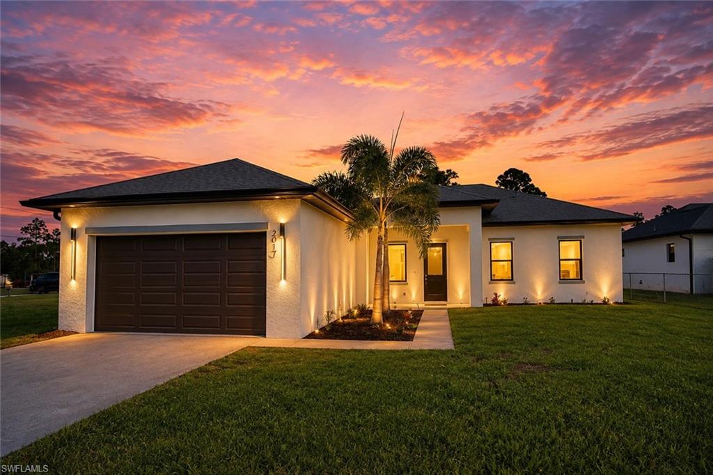 Contemporary stucco home with a dark shingle roof and integrated two-car garage