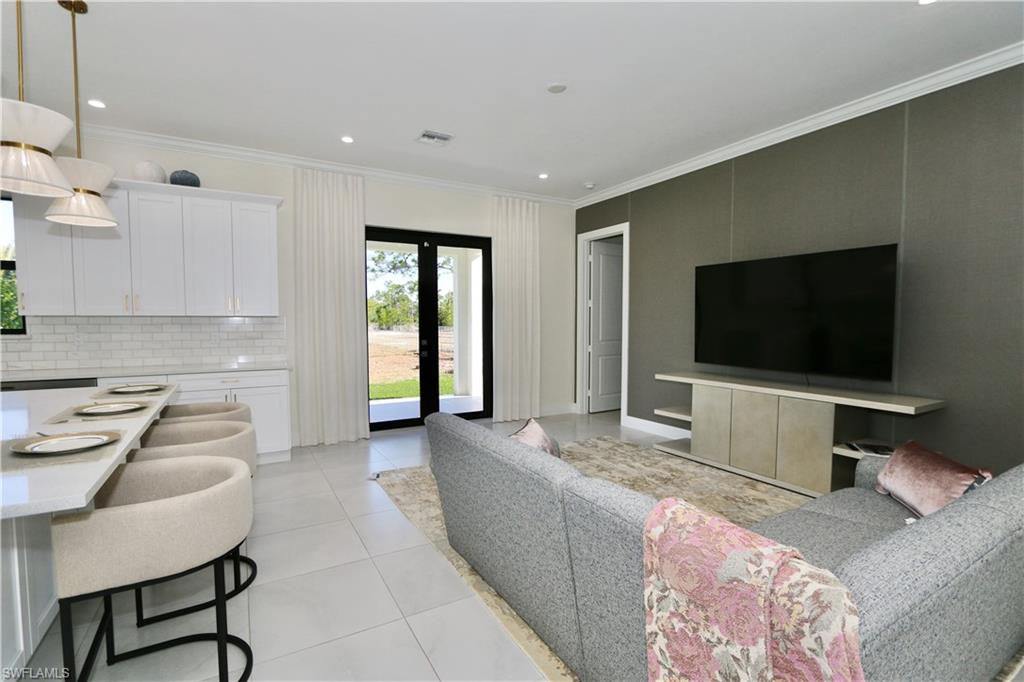 Living room with crown molding, french doors, light tile patterned floors, and recessed lighting