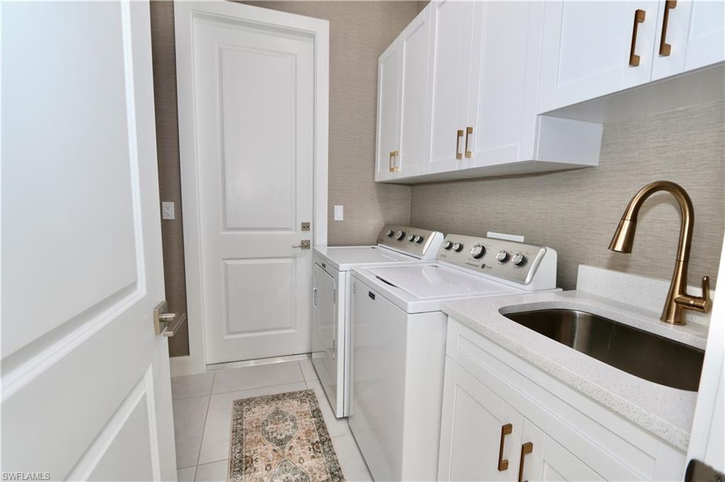 Laundry area featuring washer and dryer, cabinet space, and light tile patterned flooring