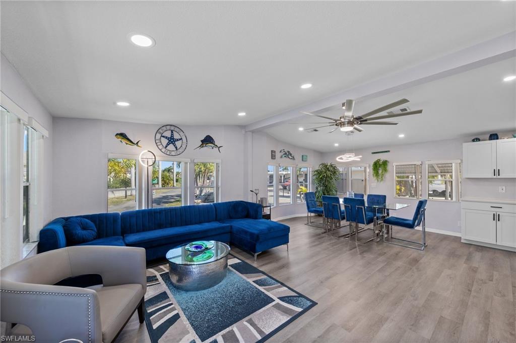 Living area featuring ceiling fan, light wood finished floors, beamed ceiling, and recessed lighting
