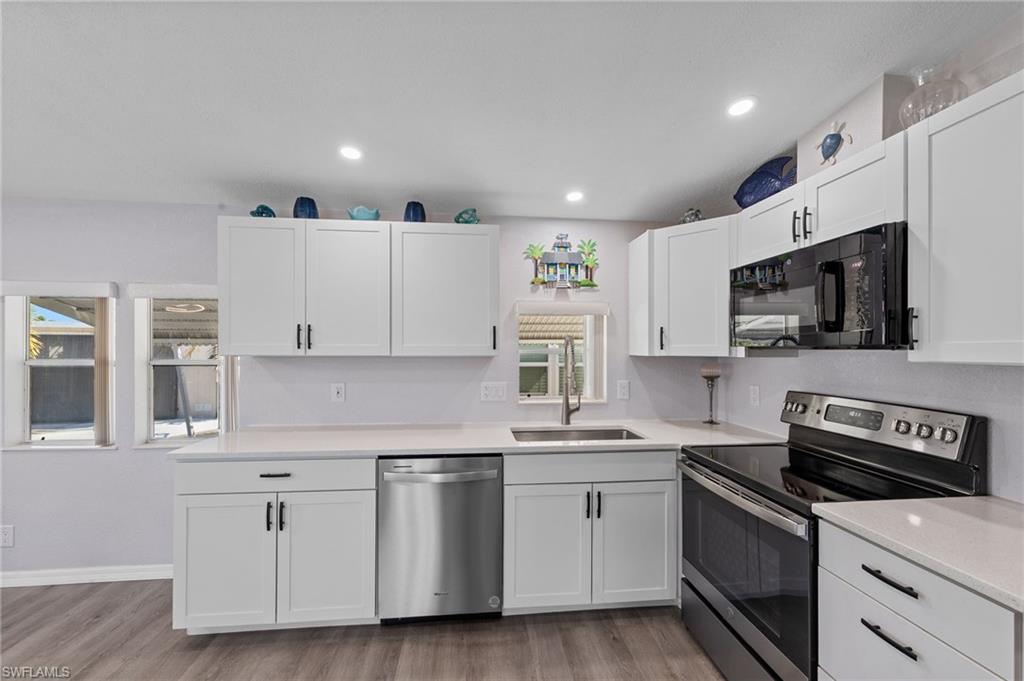 Kitchen with stainless steel appliances, white cabinets, light wood finished floors, and recessed lighting