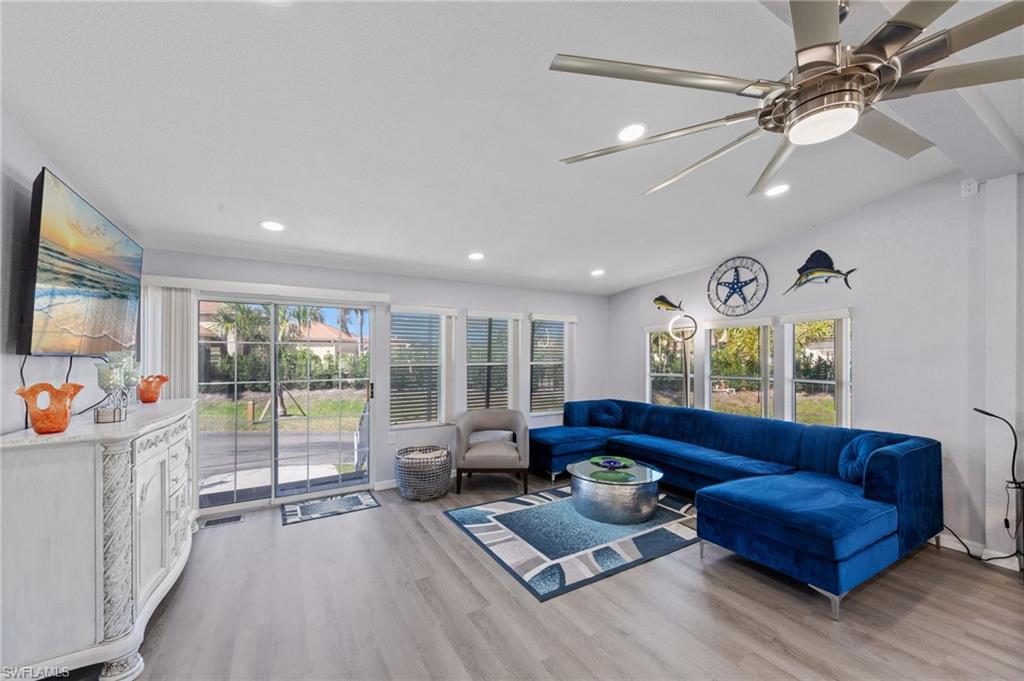 Living area featuring light wood-style floors, plenty of natural light, a ceiling fan, lofted ceiling, and recessed lighting